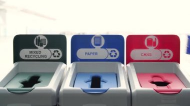 İnsanların çöp kutularına çöp attığı yakın çekim. Medya. Adam tasnif için renkli kutulara çöp atıyor. Çöpleri ayırmak doğanın geri dönüşümüne yardımcı olur ve ekolojisini destekler