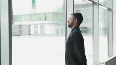 Ofis çalışanı kara bakar. Medya. İş adamı panoramik pencerelerden kar yağmasını hoş karşılamaz. Ofis çalışanı pencerenin dışındaki kar yağışına bakıyor