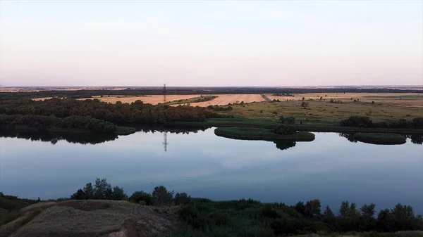 Luchtfoto van de rivier die langs landbouwgronden kronkelt. Beelden. Prachtig panoramisch uitzicht op het natuurlijke landschap met weelderige weiden en een rivier bij zonsondergang. — Stockfoto