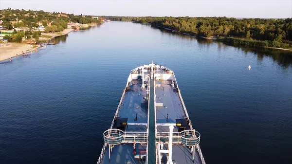 A large white cargo ship is anchored in the water area of the river. Footage. Aerial view of a ship in a river against the background of the green city on a summer sunny day. — Stock Photo, Image