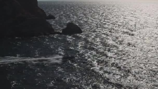 Rotsachtige archipel met een motorboot op zee, natuurlijk landschap. Neergeschoten. Luchtfoto van een speedboot in de buurt van een klif, springen op golven op een zonnige dag, concept van luxe en sport. — Stockvideo