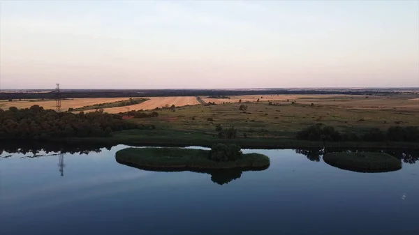 Luchtfoto panorama van prachtige landerijen badend in warm zonlicht in een seizoen van gouden oogst. Beelden. Prachtig rustig water van een rivier en de weiden. — Stockfoto