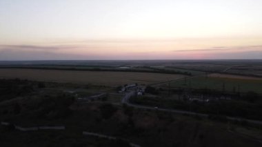 Gün batımında kırsal alan manzarası. Görüntü. Sonsuz tarım arazileri, ağaçlar ve yollar gün batımında gökyüzü arka planında yer alan tarlalar boyunca.