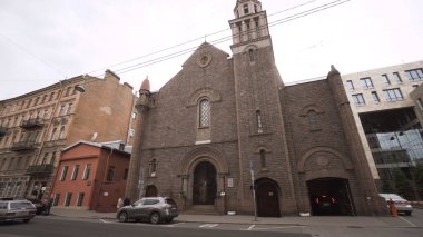 Arka plandaki kırmızı tuğlalı Katolik Kilisesi bulutlu gökyüzünde. Başla. Katolik Kilisesi 'nin eski kasabadaki Gotik tarzı. Saint Petersburg 'daki Lourdes Leydisi Kilisesi.