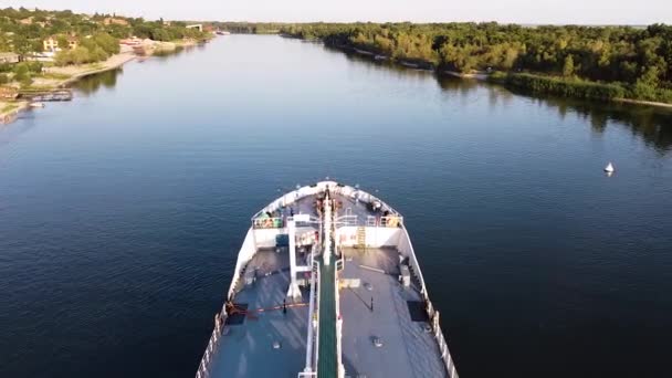 Ve vodní oblasti řeky kotví velká bílá nákladní loď. Záběry. Letecký pohled na loď v řece na pozadí zeleného města za letního slunečného dne. — Stock video