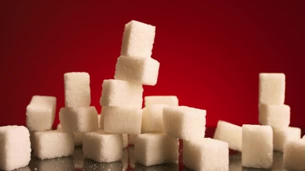Close up de pequenos cubos de açúcar caindo isolados no fundo vermelho. Imagens de stock. Conceito de doces e dieta insalubre, açúcar pressionado caindo em uma pilha de pedaços brancos. — Vídeo de Stock