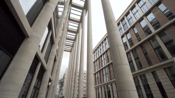 Fassade eines Gebäudes mit Marmorsäulen. Handeln. Untere Ansicht eines modernen architektonischen Komplexes, Neubau mit hellbeigen Säulen und großen Fenstern. — Stockvideo