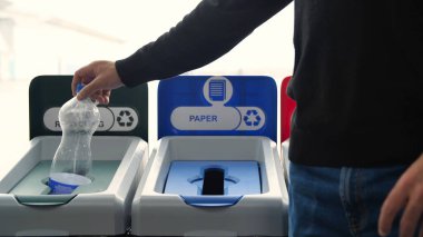 İnsanların çöp kutularına çöp attığı yakın çekim. Medya. Adam tasnif için renkli kutulara çöp atıyor. Çöpleri ayırmak doğanın geri dönüşümüne yardımcı olur ve ekolojisini destekler