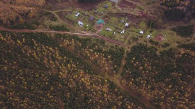 Sonbahar ormanı yakınlarındaki ender evlerin havadan görünüşü. Şarjör. Kır manzarası, sarı ağaçlar ve binalar, tarım kavramı..