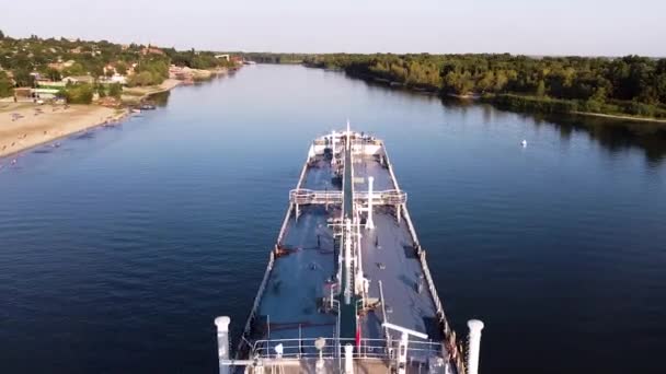 Ein großes weißes Frachtschiff liegt im Wasserbereich des Flusses vor Anker. Verfilmung. Luftaufnahme eines Schiffes in einem Fluss vor dem Hintergrund der grünen Stadt an einem sonnigen Sommertag. — Stockvideo