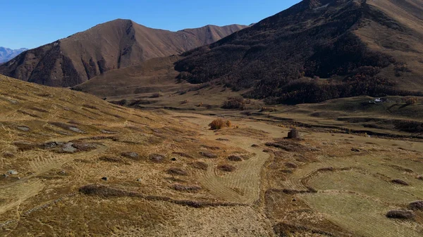 Hermosa vista aérea de paisajes montañosos abandonados naufragios casa. Filmación. Ruinas de un antiguo edificio de ladrillo en una pendiente amarilla de monturas otoñales. — Foto de Stock