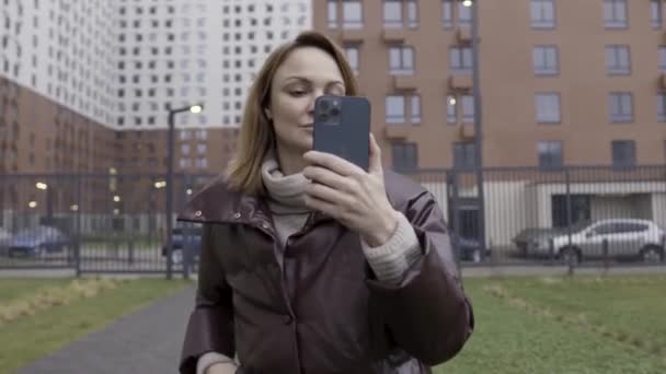 Moskwa, Rosja - 11.22.2020: Portret szczęśliwej kobiety robiącej selfie na nowym Apple Iphone 12 Pro Max. Akcja. Kobieta na zewnątrz trzymając nowe urządzenie pacyficznego niebieskiego koloru. — Wideo stockowe