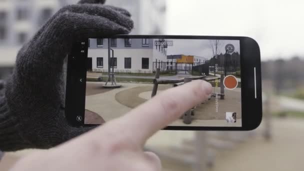 Close-up de demonstração de tecnologia de uma câmera de smartphone durante a filmagem de vídeo de um parque infantil. Acção. Dedo pressionando na tela e escolhendo o modo de zoom, modo normal e ângulo largo — Vídeo de Stock