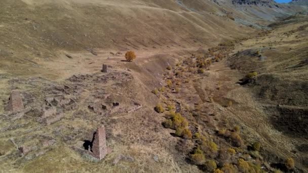 버려진 집들이 있는 험준 한 산간 풍경의 아름다운 공중 풍경. 걷기. 가을의 노란 경사지에 있는 오래 된 벽돌 건물 의유적. — 비디오
