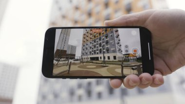 Erkek ellerinin geniş açı modunda akıllı telefondan bir video kaydetmesini kapat. Başla. Çok katlı bir binayı yeni bir cihazla çekmek inanılmaz kalitede bir resim..