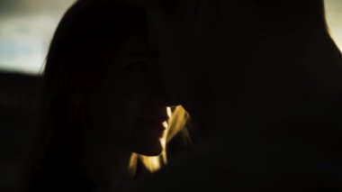 Gün batımında birbirine yakın çiftlerin siluetleri. Başla. Romantik erkek ve dişilere yakın. Tanınmayan yüzler. Gölgede saklı altın güneş ışığıyla..