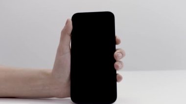 Beyaz arka planda izole edilmiş yeni ve güzel bir akıllı telefonu aktif hale getiren kadın eline yakın çekim. Başla. Modern teknolojiler kavramı, ilk kez yeni bir cihaz açılıyor..