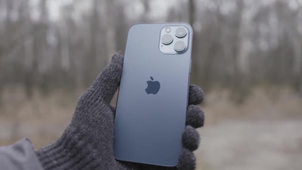 Nova Iorque, EUA - 11.11.2020: Mão na luva de malha segurando Apple iPhone 12 Pro Max Action. Demonstração ao ar livre do logotipo traseiro e câmeras. — Vídeo de Stock