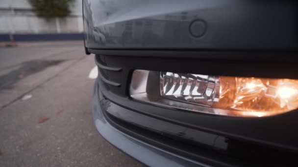 Primer plano de los faros del modelo de coche moderno. Acción. Luces de circulación diurna del coche nuevo. Hermosas luces delanteras de coche nuevo en tiempo nublado — Vídeos de Stock