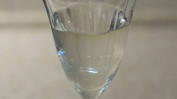Nahaufnahme von Tropfen flüssiger Vitamine, die in einem Glas in das klare Wasser fallen. Konzept. Die Einnahme von Vitaminen während Coronavirus covid 19 Pandemie, Prävention von Krankheiten. — Stockfoto