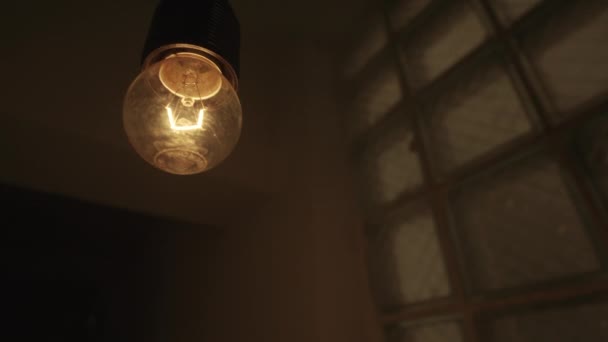 Vista inferior de uma lâmpada pendurada balançando dentro da entrada de uma buiulding. Imagens de stock. Close-up de uma lâmpada de luz amarela piscando em uma atmosfera escura e mística de um edifício. — Vídeo de Stock