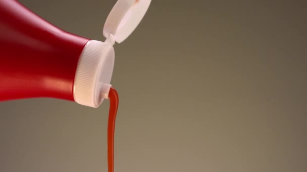 Aproape de ketchup turnat dintr-o sticlă izolată pe un fundal bej. Înregistrări stoc. Conceptul de mâncare de gătit, închideți sticla roșie de ketchup cu capac alb . — Videoclip de stoc