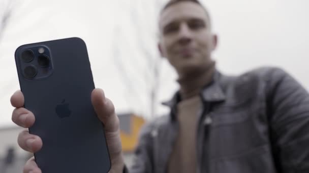 San Petersburgo, Rusia - 11.15.2020: Acercamiento de una mano masculina sosteniendo un nuevo y hermoso Iphone. Acción. Demostración del nuevo Apple Iphone 12 Pro max en color azul pacífico. — Vídeo de stock