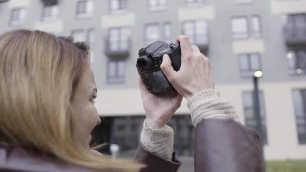 複数の階建ての住宅の建物の写真を撮る女性写真家のクローズアップ。行動だ。女性の手によるプロのカメラの側面図. — ストック動画