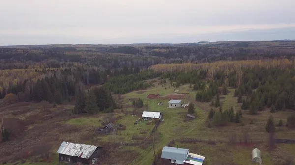 Russian village with summer old wooden houses surrounded by forests of northern Karelia, Russia. Clip. Aerial view of countryside landscape and endless Taiga on cloudy sky background. — Stock Photo, Image