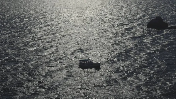 Vista aérea de un barco blanco flotando sobre aguas claras de color azul oscuro con el reflejo de la luz solar. Le dispararon. Turistas en un barco moviéndose sobre la superficie ondulada del mar, concepto de viajar. — Foto de Stock