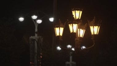 Siyah gökyüzü arka planında iki farklı sokak feneri. Stok görüntüleri. Eski moda ve modern sokak lambaları. Geceleri şehir sokaklarında sarı ve beyaz ışıklar..