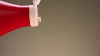 Bej arka planda izole edilmiş bir şişeden dökülen ketçapı kapat. Stok görüntüleri. Yemek pişirme kavramı, beyaz kapaklı kırmızı bir şişe ketçap..