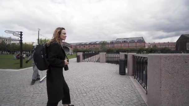 Bastante joven turista tomando fotografías durante el turismo. Acción. Mujer caminando en la calle y fotografiando un hermoso panorama de un lago de la ciudad. — Vídeo de stock