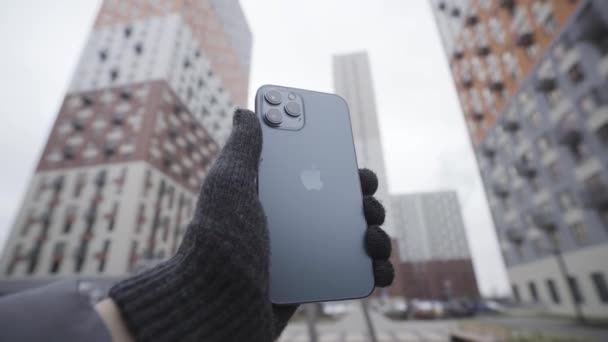 Nueva York, EE.UU. - 11.11.2020: Guante de punto hecho a mano con Apple iPhone 12 Pro Max Action. Demostración al aire libre del logotipo trasero y las cámaras. — Vídeo de stock