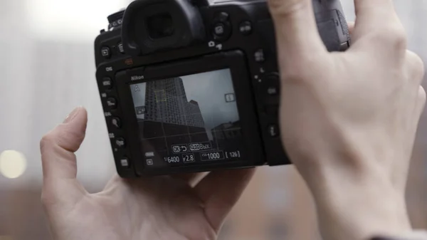 Descubra novos lugares, de perto de tirar fotos de um novo edifício alto. Acção. Mãos femininas com uma câmera profissional tirando fotos na arquitetura urbana moderna. — Fotografia de Stock