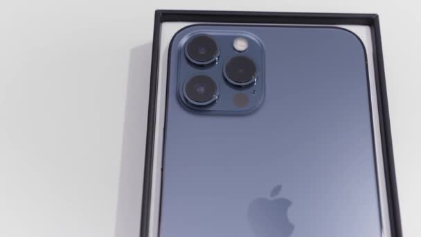 Kiev, Ukrayna-11.20.2020: bir kutudaki yeni akıllı telefonun arka görüntüsünü kapatın. Başla. En yeni Pasifik mavisi Apple Iphone 12 Pro Max beyaz arkaplanda izole edildi. — Stok video