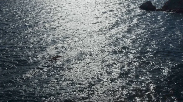 Ondas de mar con luz solar reflejada y yate de paso. Imágenes de archivo. Vista superior de hermosas olas de mar con yate de vela en el día soleado. Disparo en cámara lenta del yate que pasa — Foto de Stock