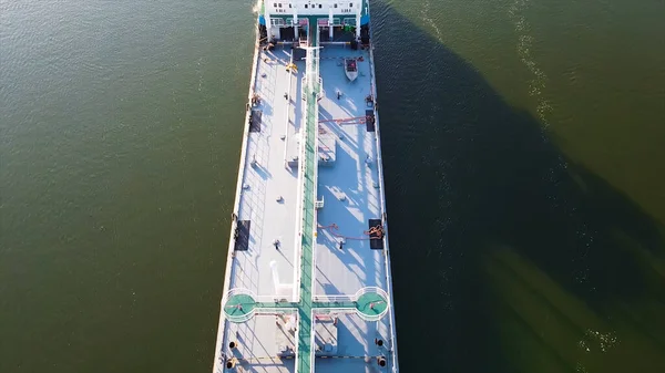 Lunga nave da carico su sfondo verde fiume. Un filmato. Vista dall'alto della nave da carico galleggiante sul fiume verde con piccole barche. Trasporto di merci per via d'acqua galleggiante sul fiume in estate — Foto Stock