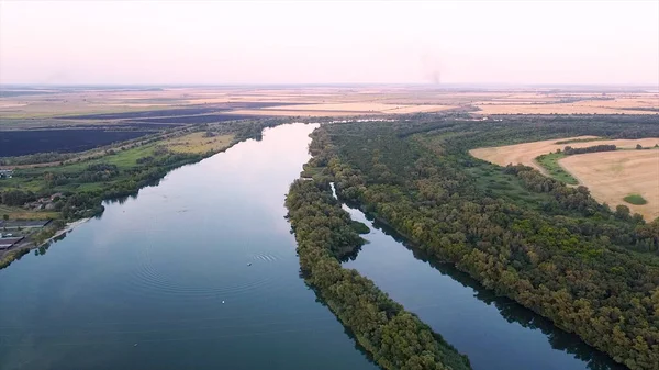 Beautiful river reflecting sky on background summer horizon. Footage. Surface of clear river reflects blue sky on background of green trees on banks. Beautiful panorama with blue river and green