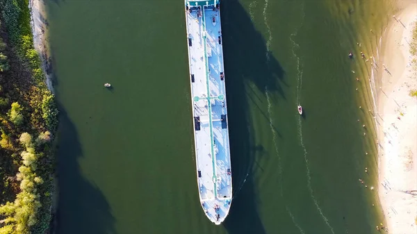 Long cargo ship on green river background. Footage. Top view of cargo ship floating on green river with small boats. Water cargo transport floating on river in summer — Stock Photo, Image