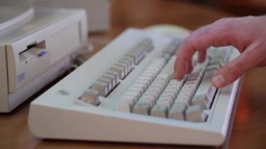 Erkeğin retro klavyeye yazışına yakın çekim. Medya. Adam eski bilgisayarı kullanıyor, eski klavyeye basıyor. Çalışan eski bilgisayar ekipmanları