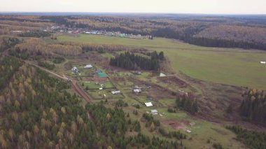 Küçük bir köyün üzerinden hava manzarası. Şarjör. Tarım faaliyetleri için ekolojik alan ve karışık sonbahar ormanı ve yeşil alan yakınında yaşayanlar için.