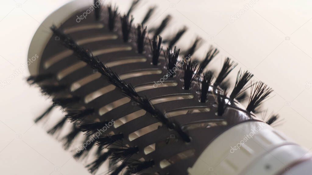 Close up of hot air rotating hair styler in female hands. Concept. Woman hands showing the work of air dryer isolated on white background, concept of beauty.