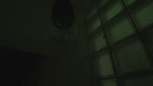 Lampadina senza lampada appesa al soffitto al buio. Filmati delle scorte. Illuminazione di un vecchio e cupo con luci colorate sul muro, concetto di festa. — Video Stock