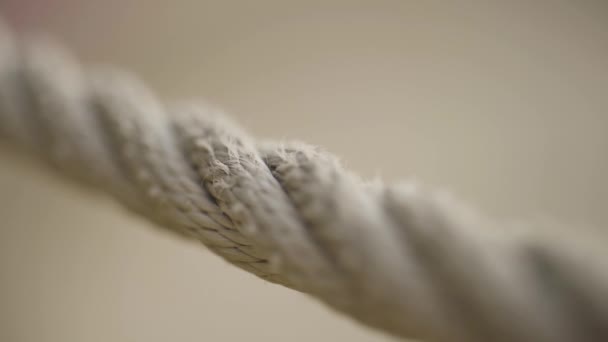 Extrême gros plan d'une corde sur fond beige flou. L'action. Vue macro d'une corde beige tendue avec mise au point de la caméra glissant lentement le long de la corde. — Video