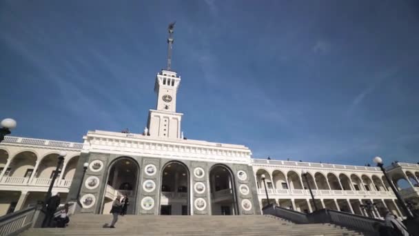 河站立面。行动。美丽的白色建筑,钟塔与蓝天相映成趣.人们从莫斯科的北部河站出发进行游轮旅行。北河车站-建筑 — 图库视频影像