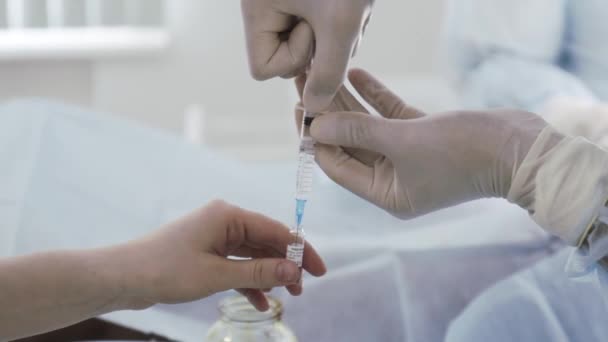 The doctor draws medicine into a syringe from an ampoule. Action. Close up of doctor hands in protective gloves preparing antiviral drug, vaccine against coronavirus covid 19. — Stock Video