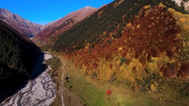 Sonbaharda Dağ Vadisi 'nde kurumuş nehir. Görüntü. Nehir vadisi ve renkli sonbahar yamaçlarıyla güzel dağ manzarası. Güneşli bir günde sonbahar dağı manzarası