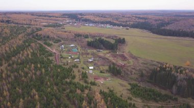 Sonsuz bir sonbahar ormanı ve bir köyün manzaralı panoramik manzarası. Şarjör. Kırsal alan, karışık orman, kırsal bir köyün geleneksel evleri, yaşamak için ekolojik bir yer..