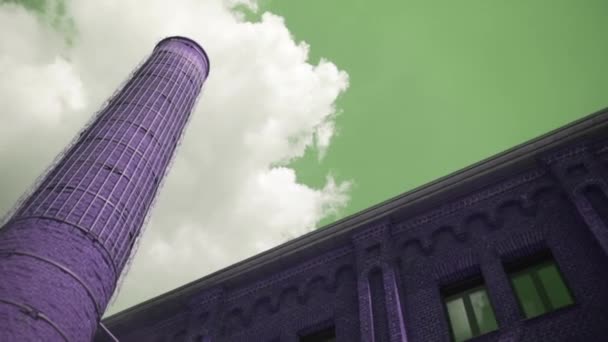 Industrial old red brick chimney on blue cloudy sky background. Action. Bottom view of an old abandoned factory building with a tall chimney, concept of heavy industry. — Stock Video